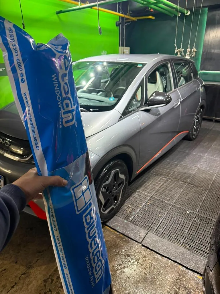 Profissional preparando película nano cerâmica sob medida para instalação